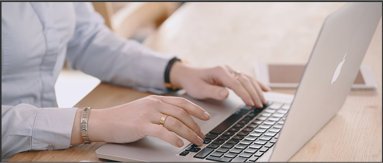 close-up of woman's hands typing on laptop computer